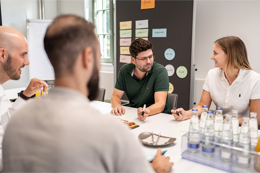 A group of people are sitting around a table with bottles of water on it.