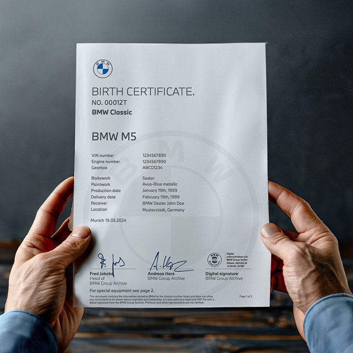 Two hands hold the birth certificate of a BMW M5