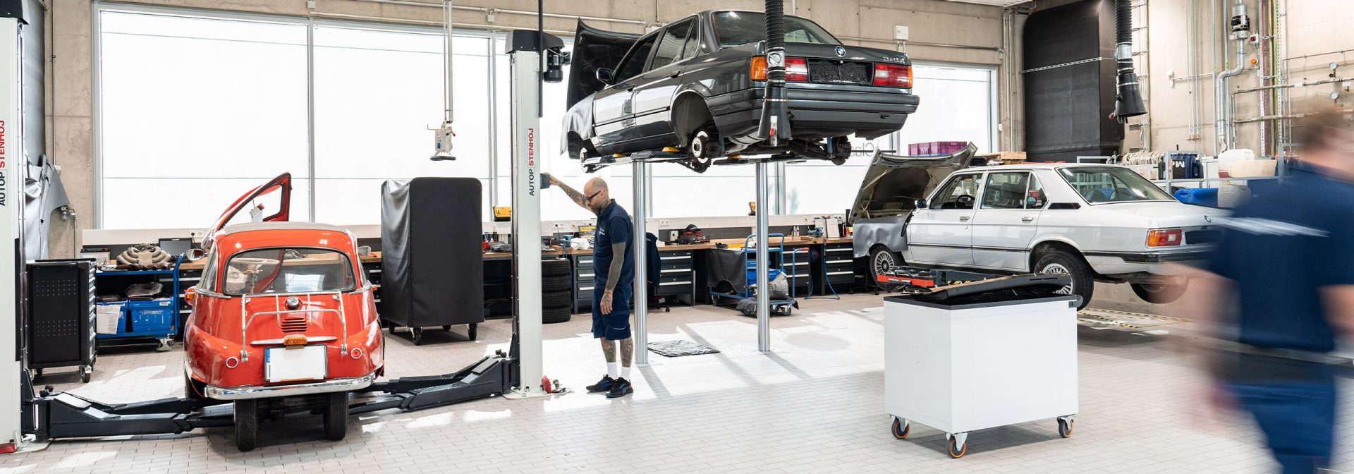 A man works on a BMW Classic model in a garage to make repairs and improve performance.