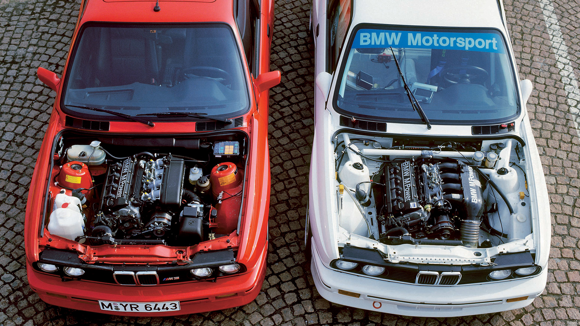 Two cars parked next to each other with an opened hood