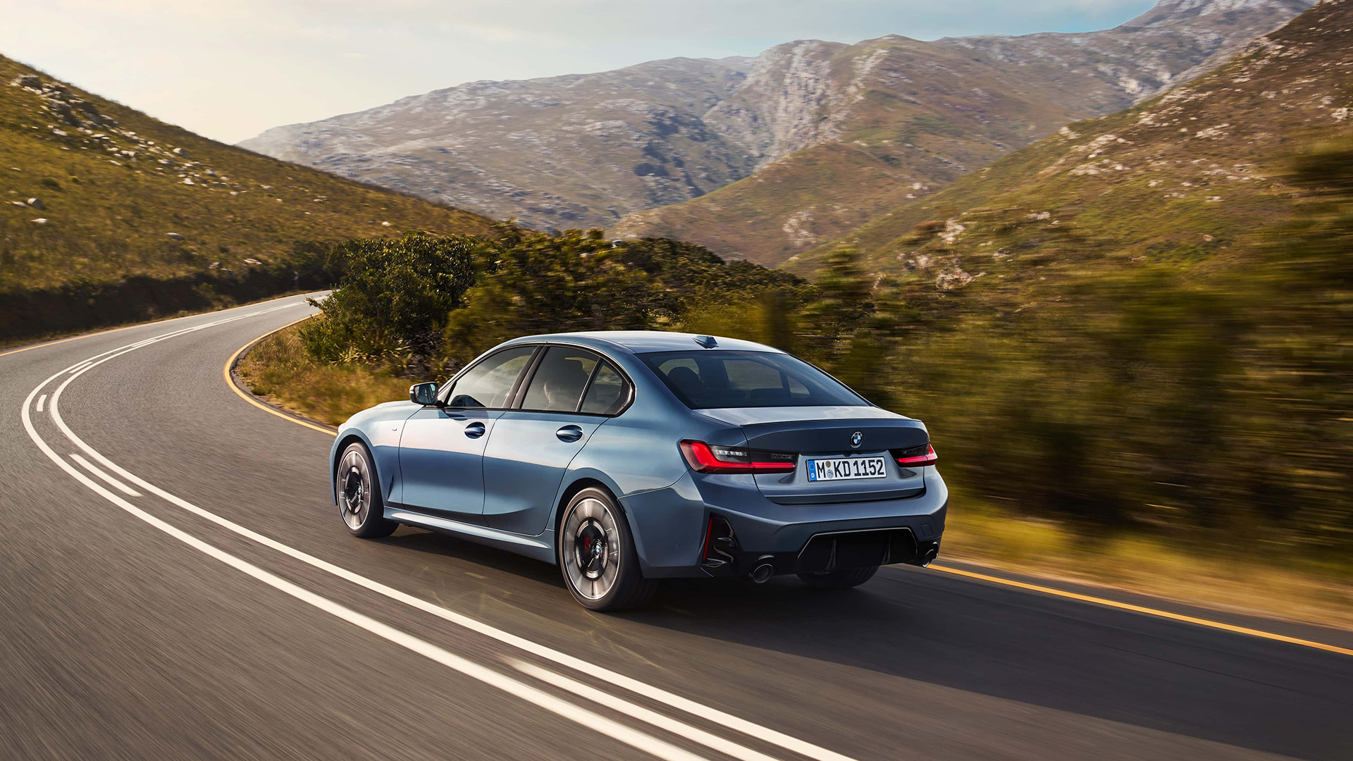 Back view of a 7th generation BMW 3 series driving on a mountain road